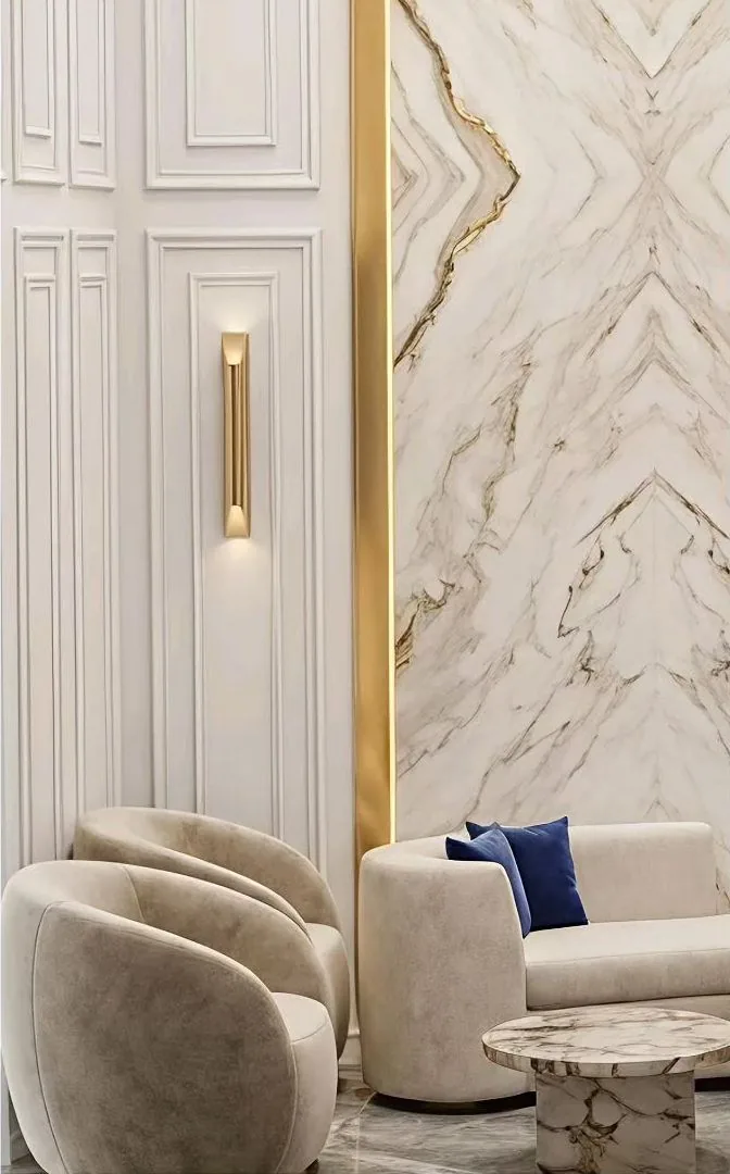 Book-matched marble wall with brass trims and curved lounge chairs